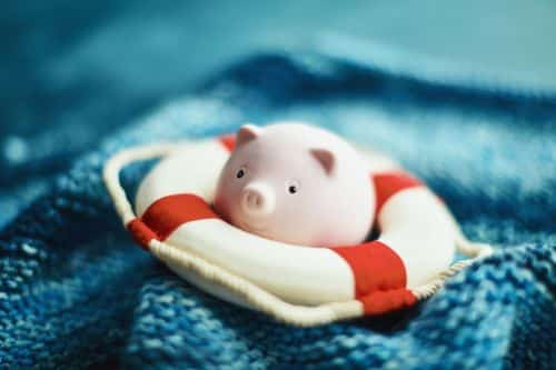 Little pink piggy bank with life belt in handmade waves - Visual concept for legal blog discussing the pros and cons of offshore asset protection trusts.