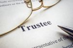 Word trustee near glasses and the pen. Visual concept for a legal blog discussing the key duties of a trustee.
