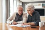 A senior couple sitting together and going through their estate plans and living trust documents. A visual concept for a legal blog discussing when and how to update a living trust.